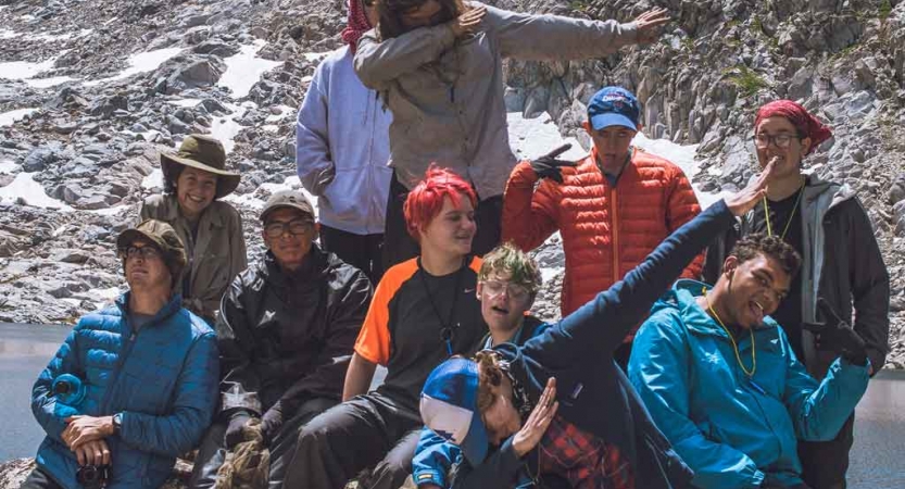 A group of students pose for a photo on rocky terrain 